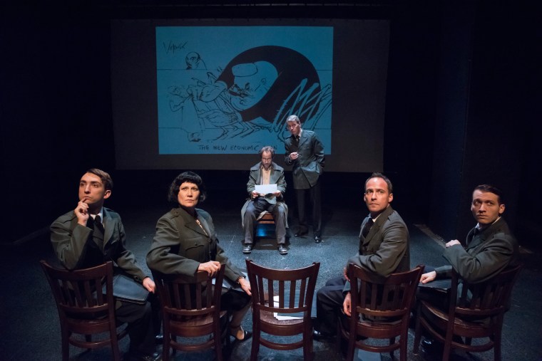 [L-R upstage] Alex Draper, Jonathan Tindell + assembled interrogators. Image by Stan Barouh with Gerald Scarfe projected illustration.